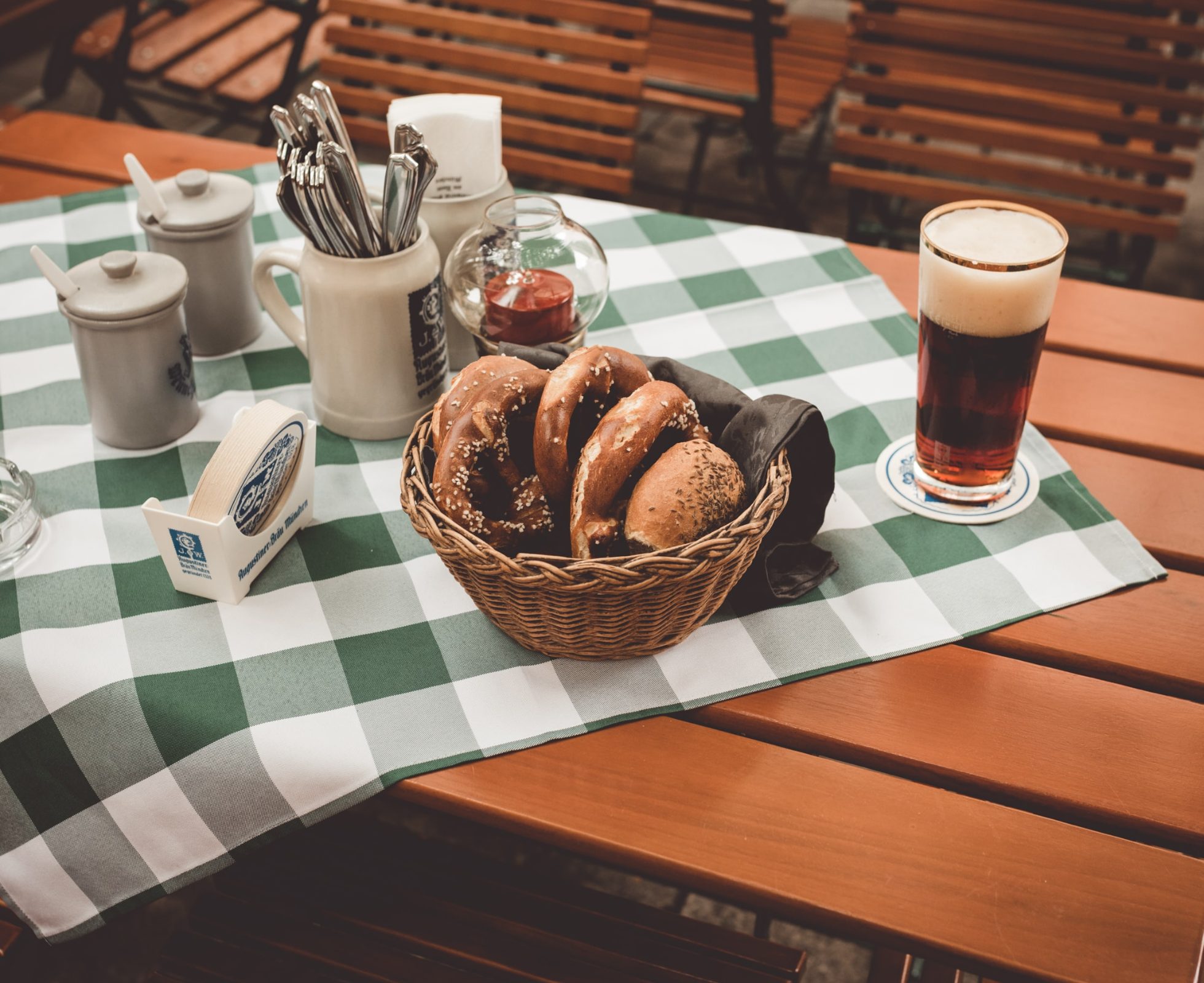 Pretzels in a basket and beer in a mug on a table covered with a checkered tablecloth