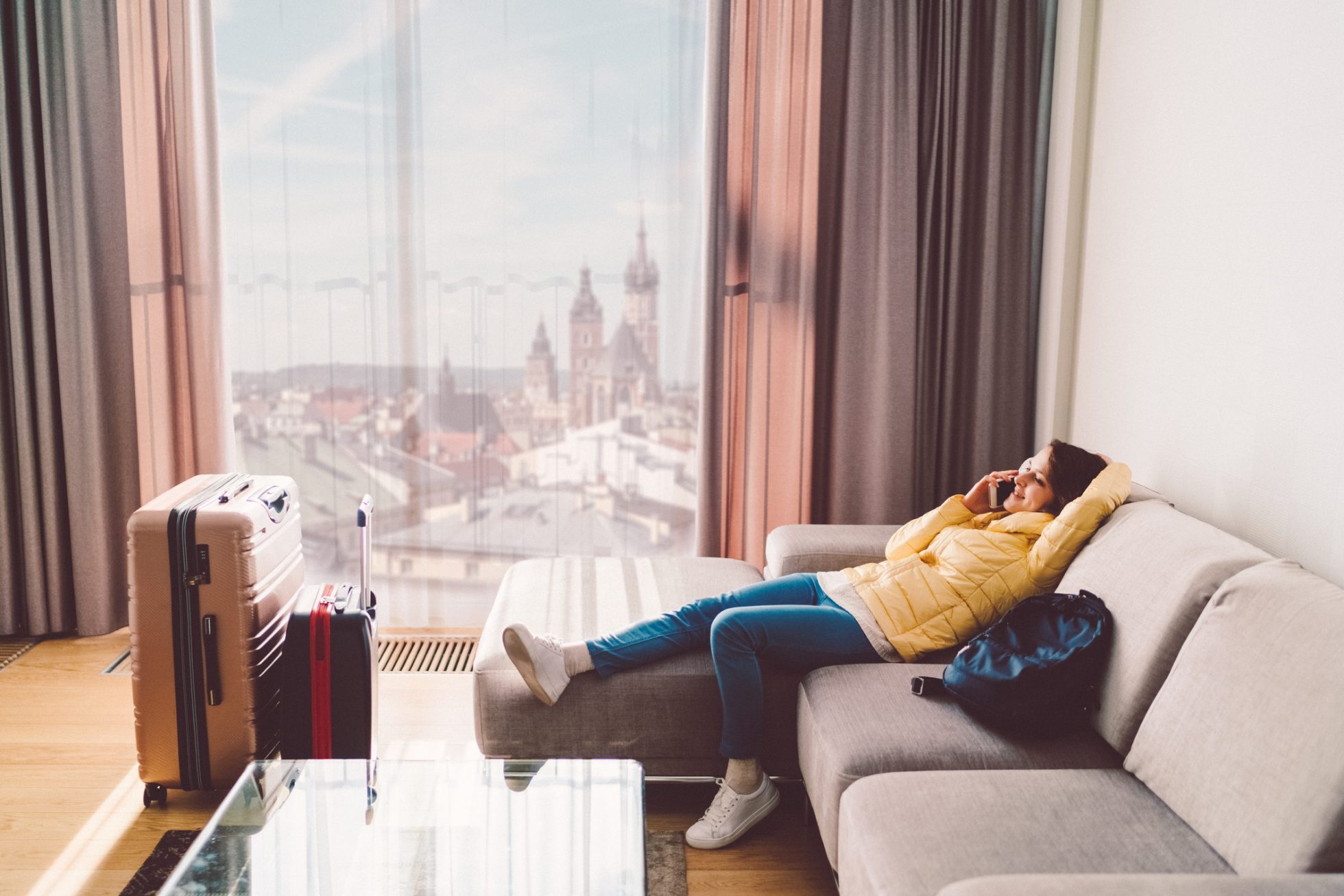 Happy woman lying down at the sofa and talking on phone