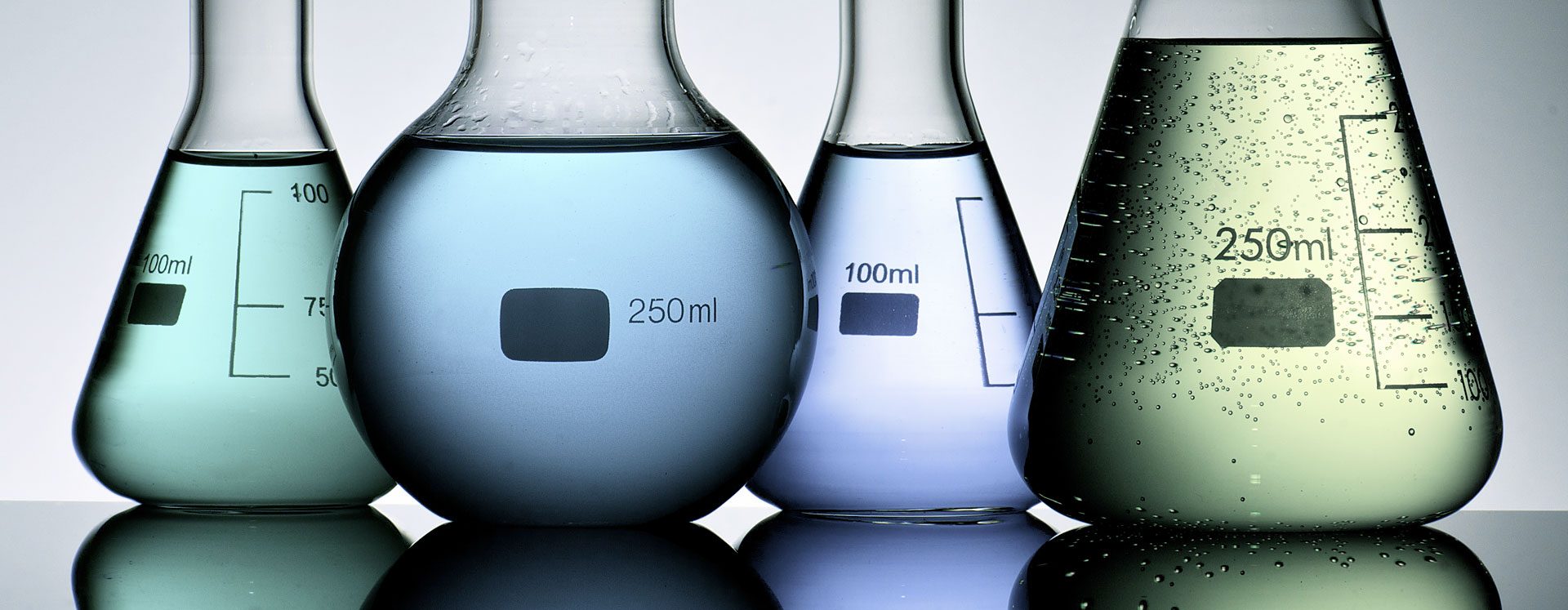 Four glass chemical tubes filled with colorful fluids